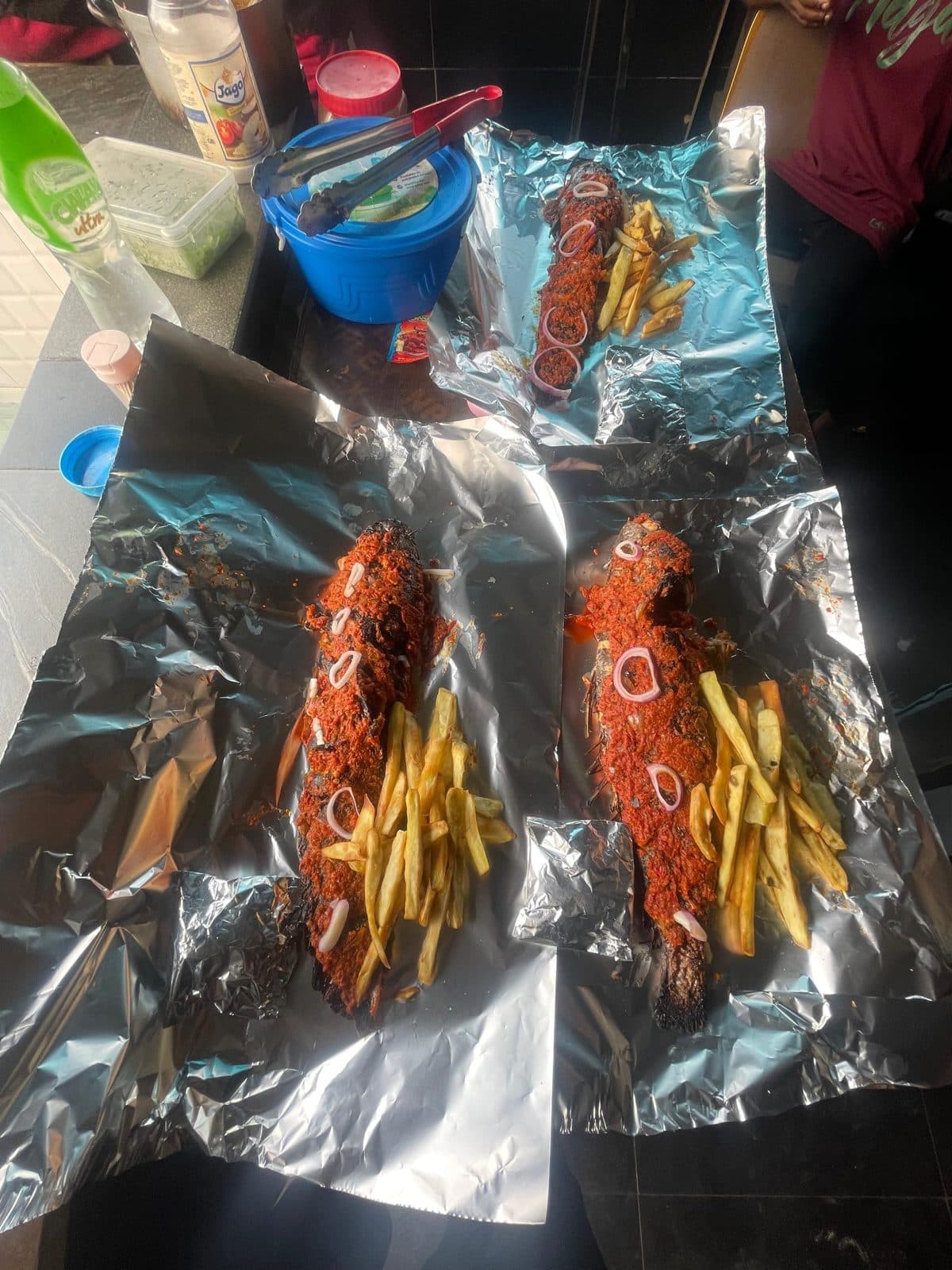 Three grilled catfish with pepper sauce and chips on foil
