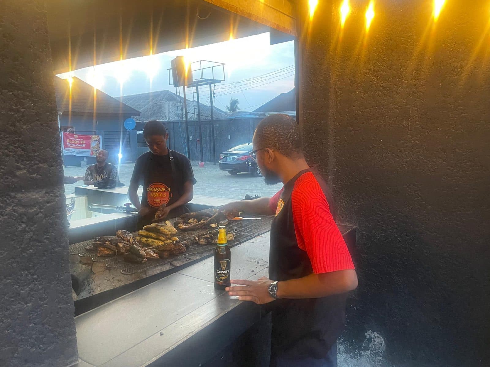 Fish, plantain and yam on the open charcoal grill at Charlie's Grill at dusk